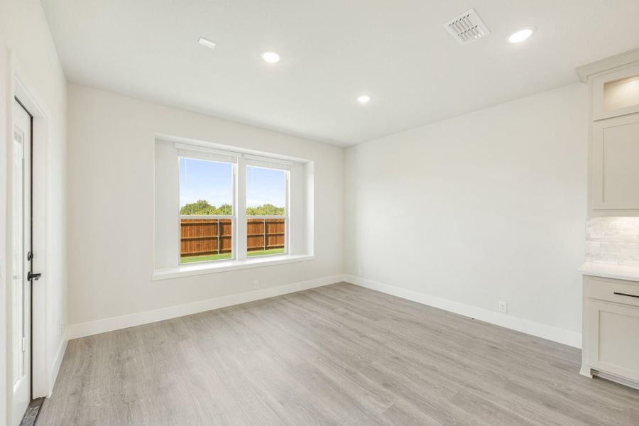 Empty room with light gray wood floors, white walls, recessed lighting, and a double window