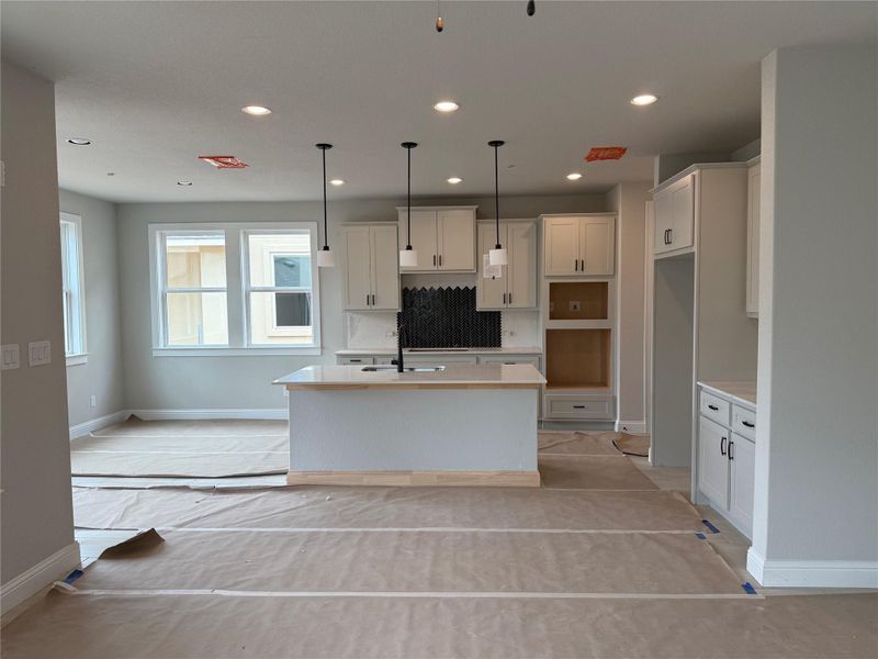 Kitchen featuring an island with sink, recessed lighting, white cabinets, decorative light fixtures, and decorative backsplash Kitchen featuring an island with sink, recessed lighting, white cabinets, decorative light fixtures, and decorative backsplash