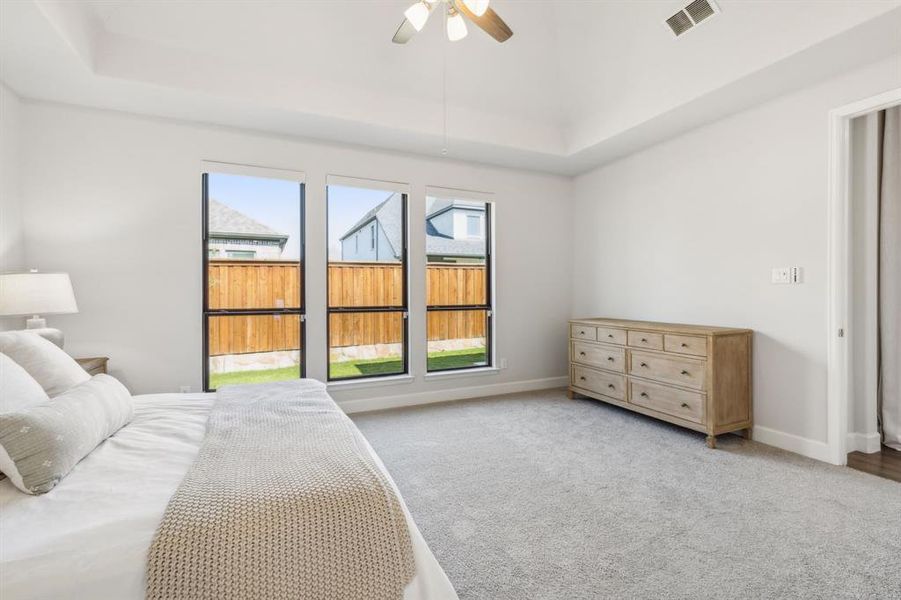 Carpeted bedroom featuring a tray ceiling and ceiling fan