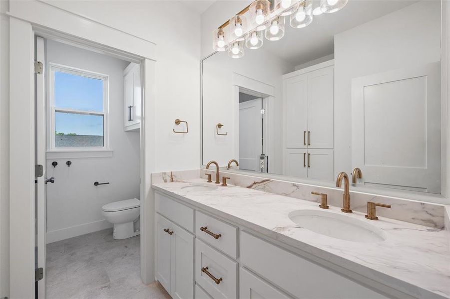Dual vanity with integrated sinks, marble-finish countertop, and brushed brass fixtures