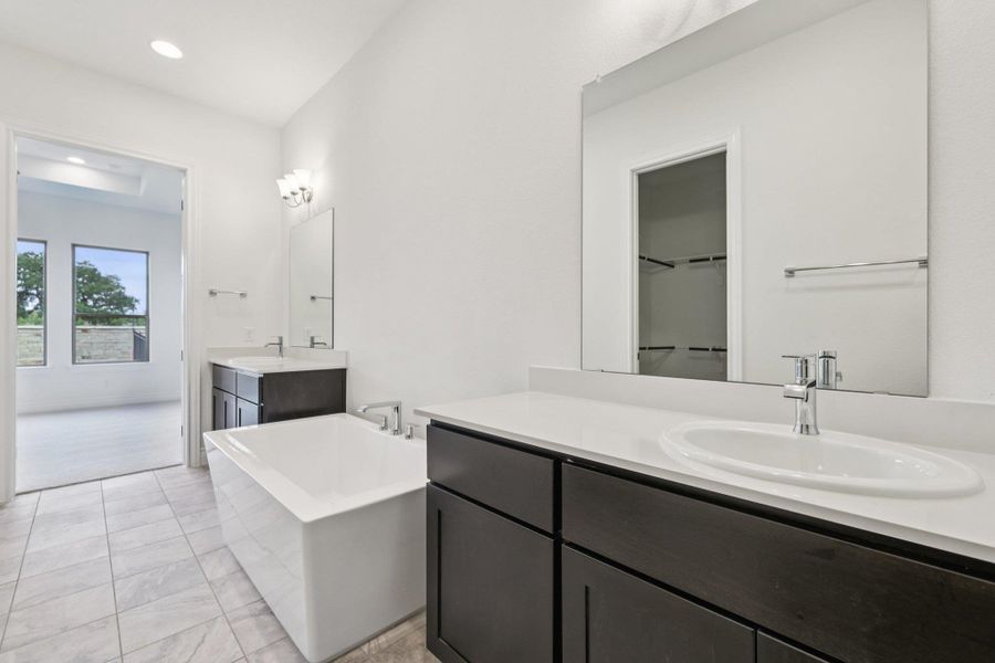 Full bathroom with a freestanding tub, two vanities, and recessed lighting