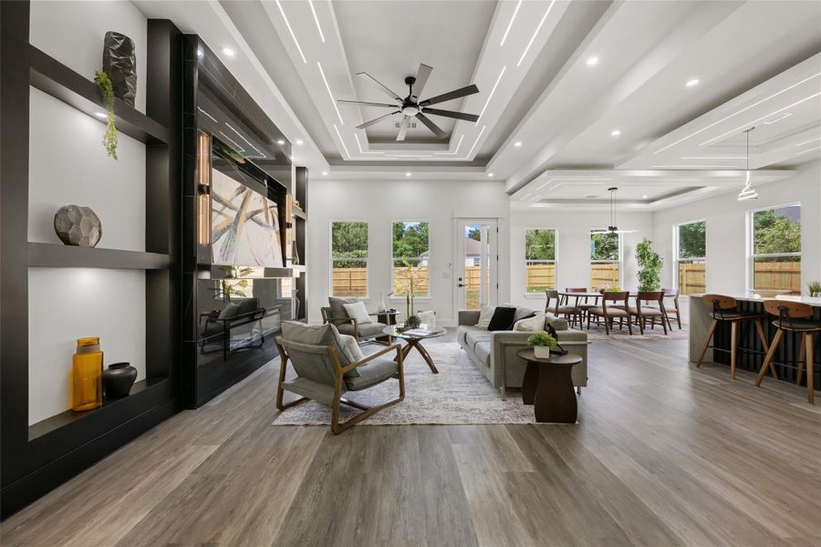 Open-concept living area featuring wood-finish flooring, a contemporary built-in media center with shelving, and multiple windows