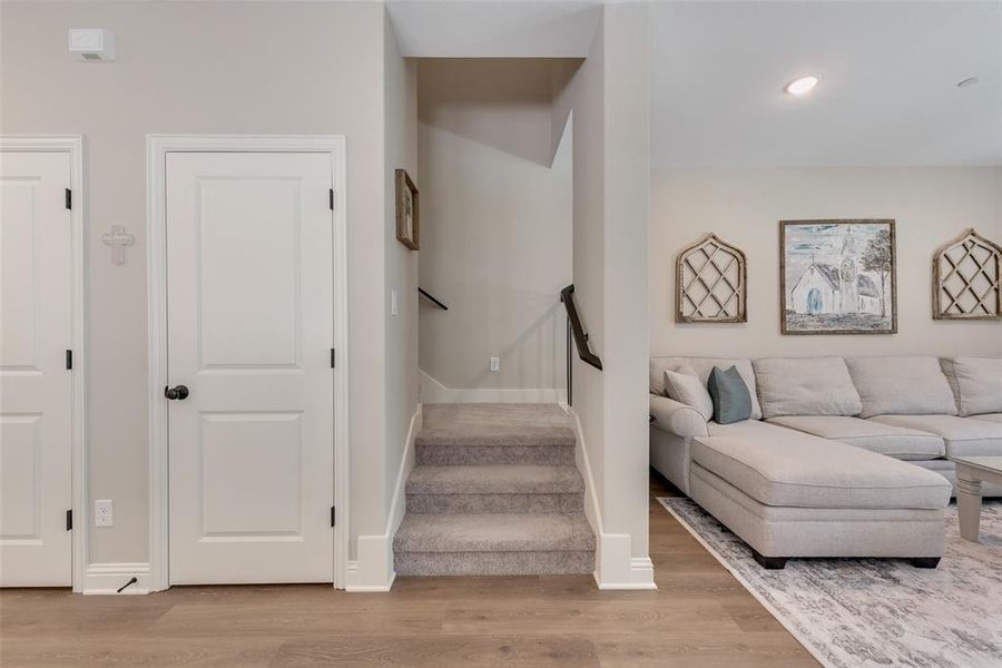 Living area upgraded with upgraded Pergo water tight laminate wood look flooring, light neutral wall tones, white trim, and a carpeted staircase with a dark wood handrail Living area upgraded with upgraded Pergo water tight laminate wood look flooring, light neutral wall tones, white trim, and a carpeted staircase with a dark wood handrail