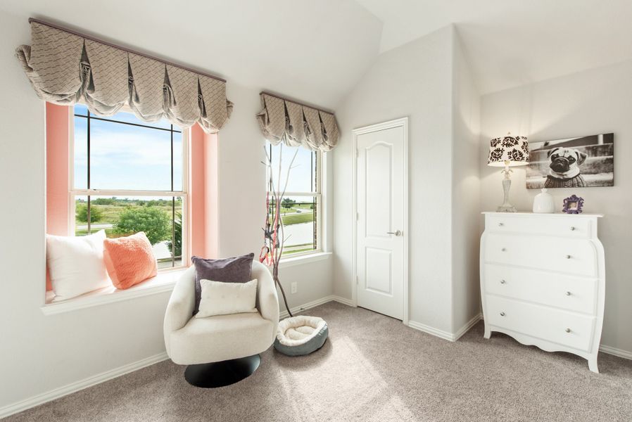 Bedroom with window seat, accent chair, white dresser, and two windows with decorative valances
