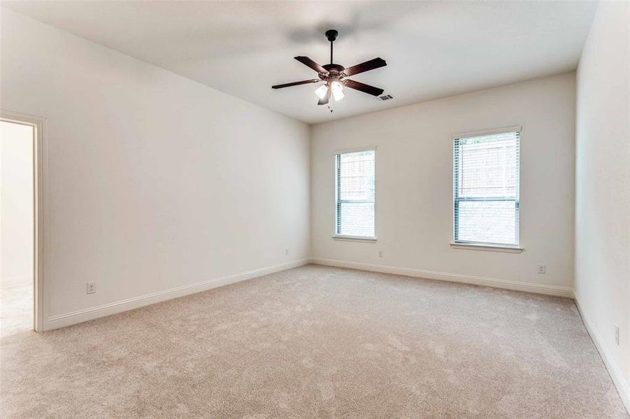 Spare room featuring light colored carpet, ceiling fan, and baseboards