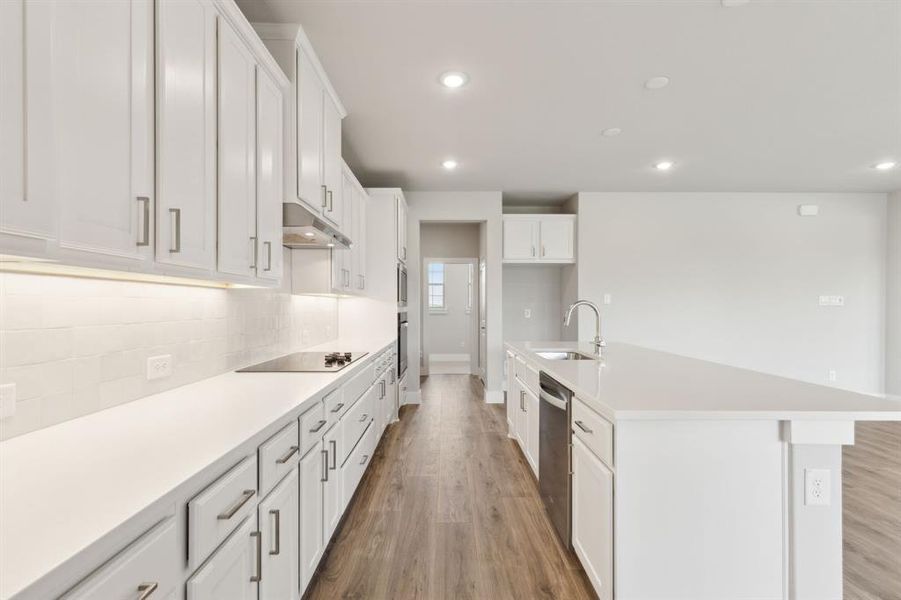 Kitchen featuring under cabinet range hood, black electric stovetop, light wood-style flooring, decorative backsplash, and recessed lighting Kitchen featuring under cabinet range hood, black electric stovetop, light wood-style flooring, decorative backsplash, and recessed lighting