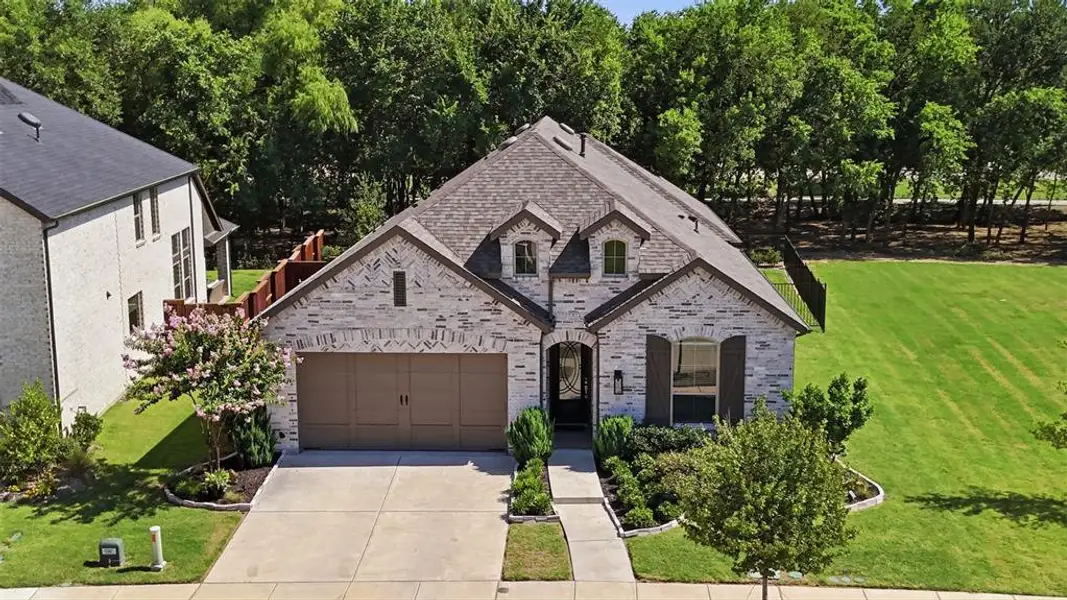 Stone facade residence featuring an attached two-car garage, dormer windows, and a manicured front yard Stone facade residence featuring an attached two-car garage, dormer windows, and a manicured front yard