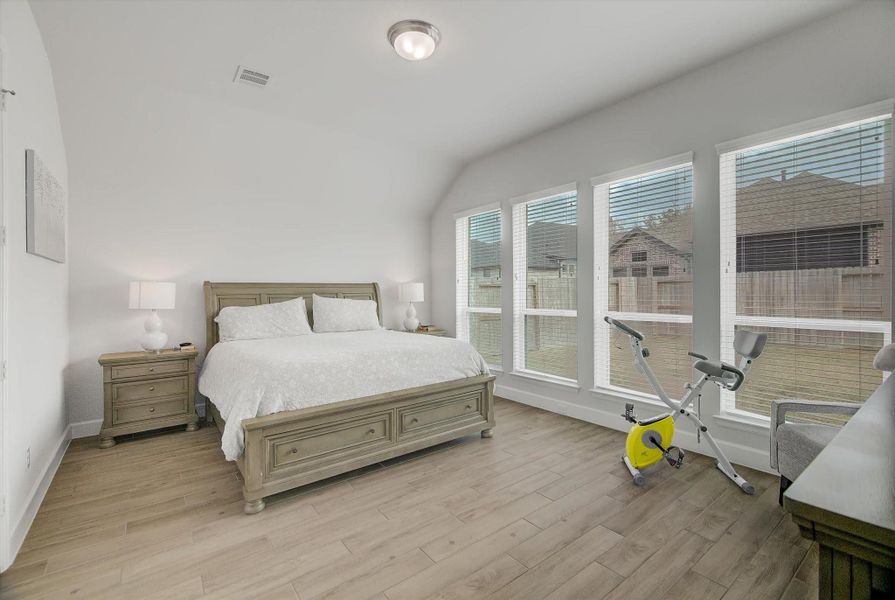 The primary bedroom continues the elegant tile flooring from the main living area and opens into a spacious 18×14 retreat highlighted by a wall of windows that fills the room with natural light and creates a serene, airy atmosphere.