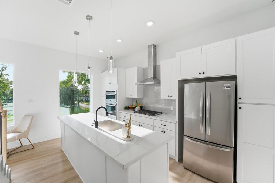 Bright, modern kitchen showcasing white shaker cabinetry, quartz countertops, stainless steel appliances, pendant lighting, and a spacious center island, all complemented by abundant natural light and a clean, contemporary design.
