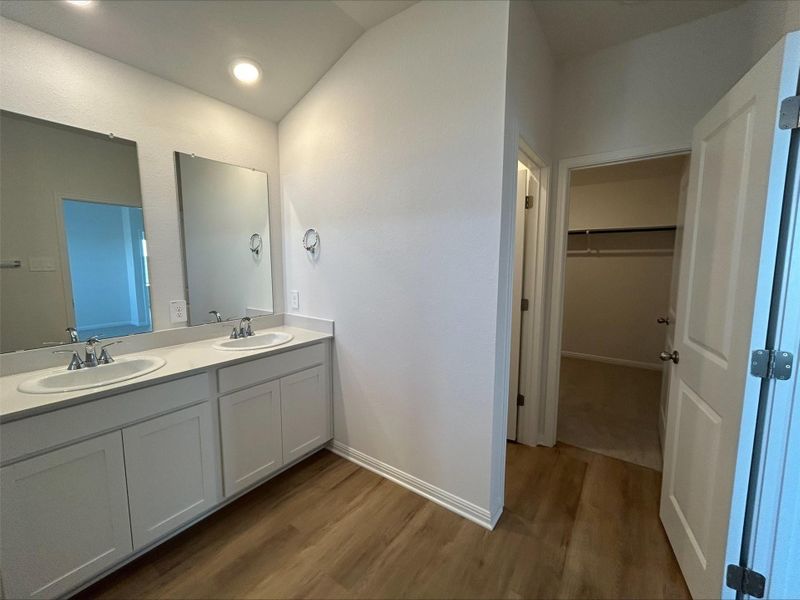 Full bathroom featuring a spacious closet, double vanity, dark wood finished floors, and recessed lighting
