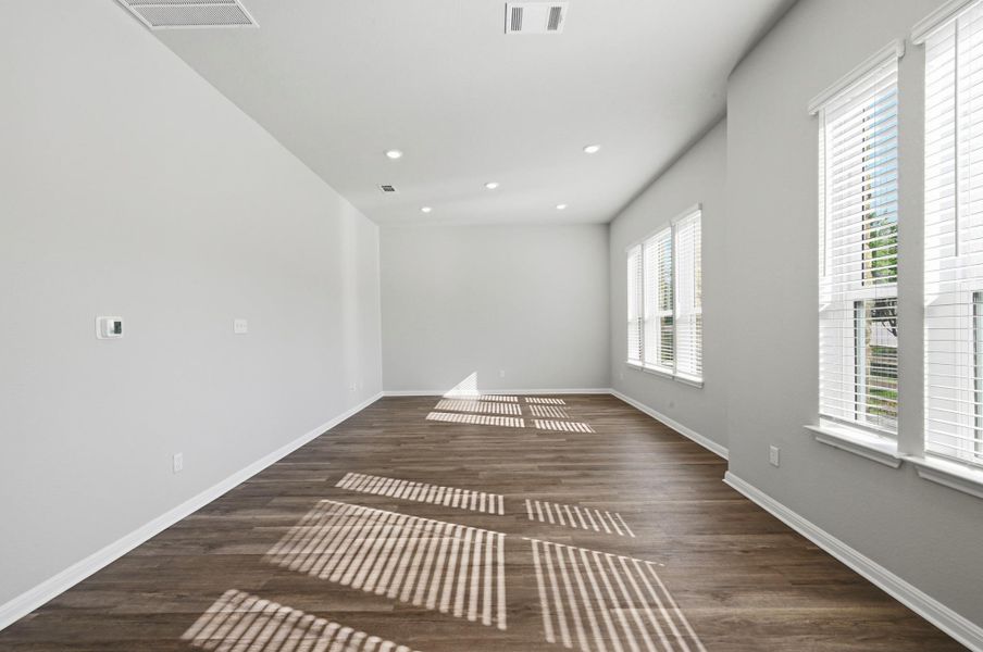 Spacious room featuring wood-finish flooring, recessed lighting, multiple windows with blinds, and light-toned walls Spacious room featuring wood-finish flooring, recessed lighting, multiple windows with blinds, and light-toned walls