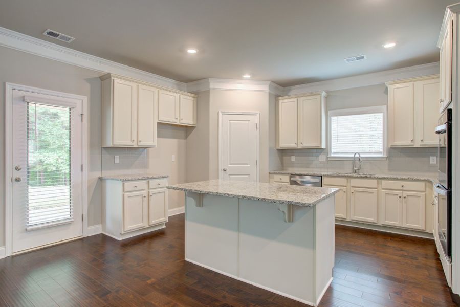 Open floor plan presents a gourmet kitchen with a large center island and ample cabinetry with a view of the breakfast area and great room