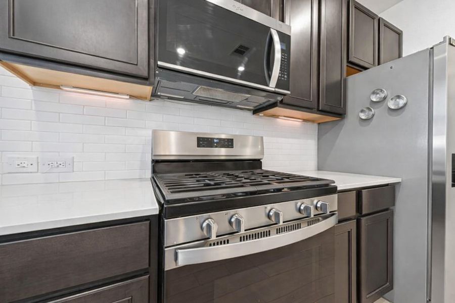 Sleek U-shaped kitchen with bright subway tile, expansive counters, and abundant cabinetry throughout.