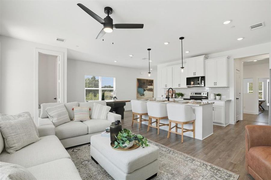 Living area with wood finished floors, plenty of natural light, ceiling fan, and recessed lighting Living area with wood finished floors, plenty of natural light, ceiling fan, and recessed lighting