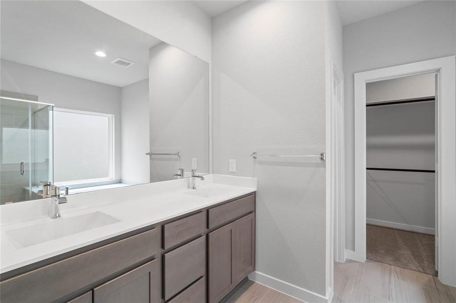 This primary bathroom is definitely move-in ready! Featuring stained cabinets with light countertops, spacious walk-in closet with shelving, high ceilings, custom paint, sleek modern finishes.