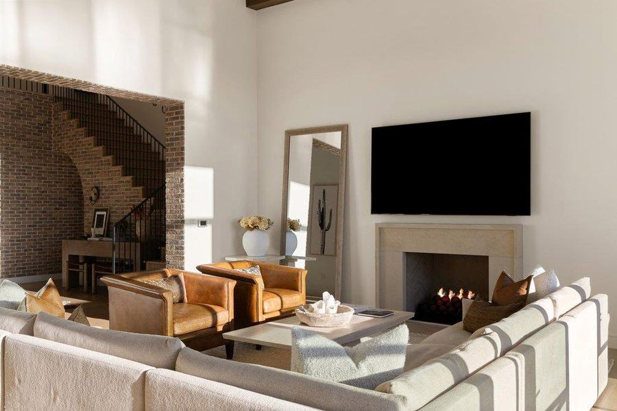 Living room with a high ceiling, a fireplace, and brick wall