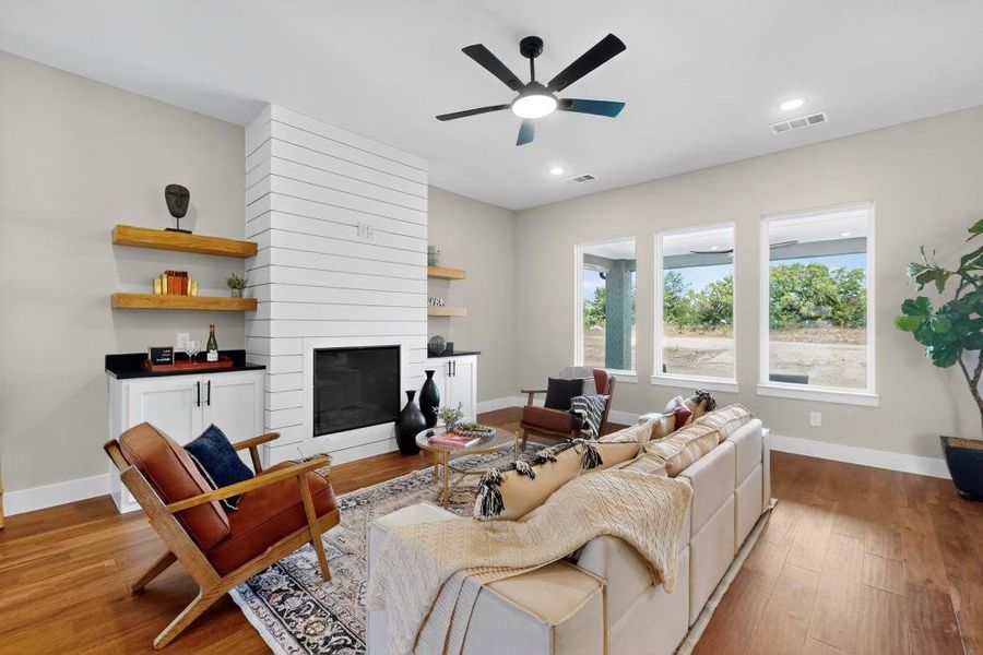 Living area featuring ceiling fan, wood finished floors, a large fireplace, and recessed lighting