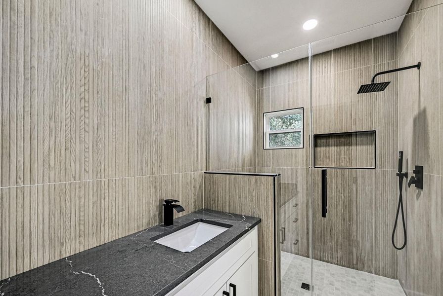 Bathroom featuring a shower stall, vanity, tile walls, and recessed lighting
