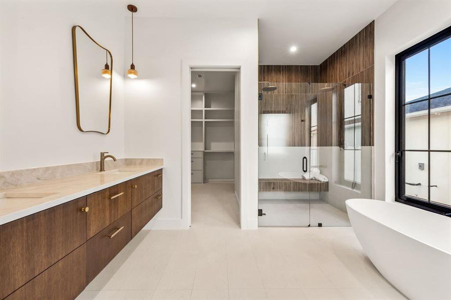 Full bathroom featuring double vanity, a shower stall, a freestanding tub, a spacious closet, and light tile patterned floors Full bathroom featuring double vanity, a shower stall, a freestanding tub, a spacious closet, and light tile patterned floors