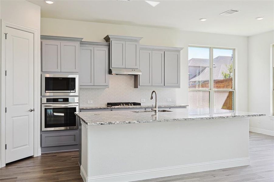 Kitchen featuring sink, hardwood / wood-style flooring, tasteful backsplash, gray cabinetry, and stainless steel appliances