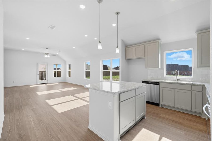 Kitchen featuring plenty of natural light, a center island, recessed lighting, light stone counters, and pendant lighting Kitchen featuring plenty of natural light, a center island, recessed lighting, light stone counters, and pendant lighting