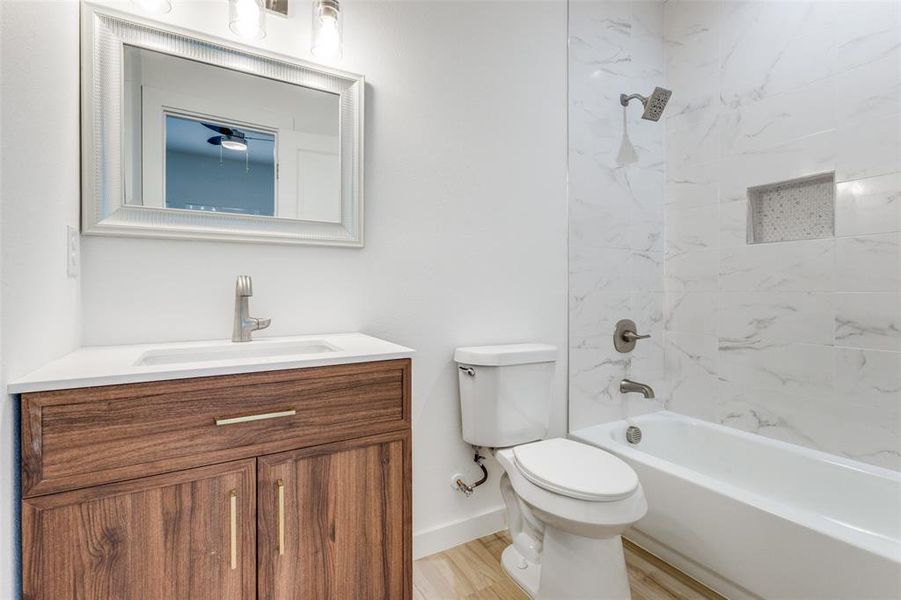 Primary bedrrom-Full bathroom featuring vanity, tiled shower / bath, hardwood / wood-style flooring, and toilet