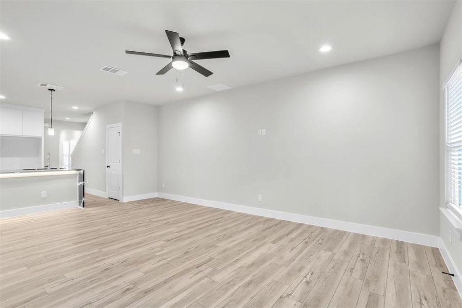 Unfurnished living room featuring ceiling fan and light hardwood / wood-style flooring