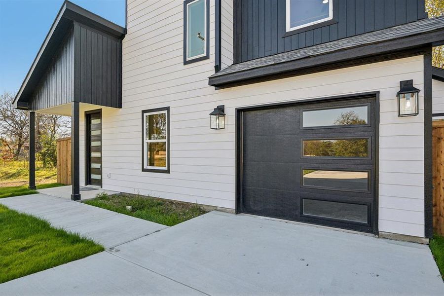 Doorway to property with board and batten siding, a garage, and driveway