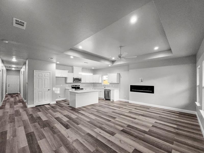 Kitchen with appliances with stainless steel finishes, baseboards, a raised ceiling, open floor plan, and ceiling fan Kitchen with appliances with stainless steel finishes, baseboards, a raised ceiling, open floor plan, and ceiling fan