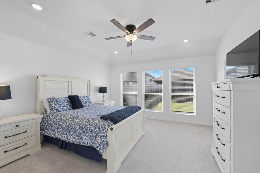 The bright, spacious master bedroom features a ceiling fan, recessed lighting, and three wide windows offering ample natural light and a view of the backyard. The bright, spacious master bedroom features a ceiling fan, recessed lighting, and three wide windows offering ample natural light and a view of the backyard.