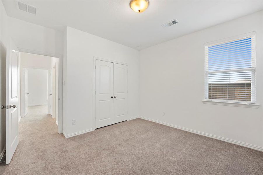 Unfurnished bedroom featuring light carpet and a closet