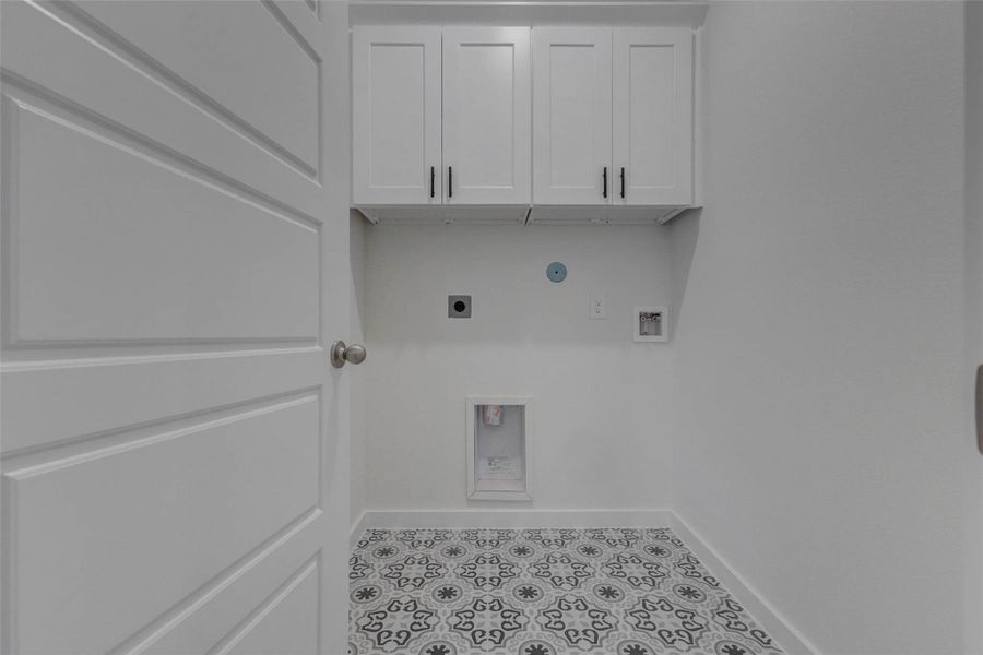 Style meets functionality in this beautifully finished laundry room. Designer tile flooring adds personality, while upper cabinetry offers convenient storage for cleaning supplies and laundry essentials. Thoughtful layout and utility connections make daily tasks easier in this clean and charming space.