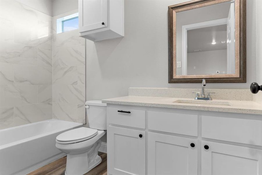 Bathroom featuring vanity, toilet, wood finished floors, and washtub / shower combination Bathroom featuring vanity, toilet, wood finished floors, and washtub / shower combination
