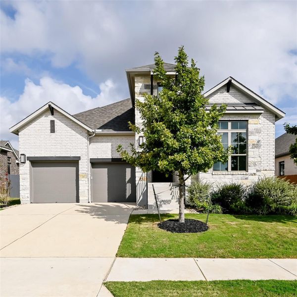 View of front of property with stone siding, driveway, a front lawn, and an attached garage View of front of property with stone siding, driveway, a front lawn, and an attached garage