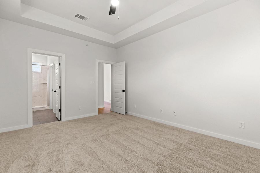 An airy primary bedroom suite features soft carpeting and direct bathroom access. An airy primary bedroom suite features soft carpeting and direct bathroom access.