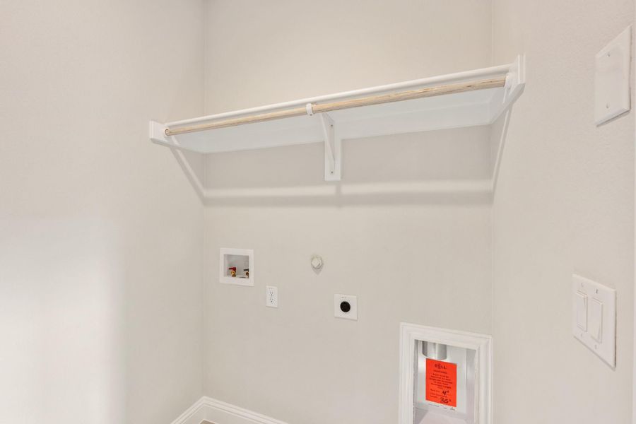 Laundry room with wall-mounted shelf, hanging rod, washer hookups, and dryer vent connection