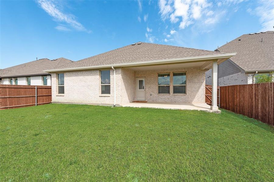 Rear view of house featuring a patio area, a fenced backyard, a shingled roof, and brick siding