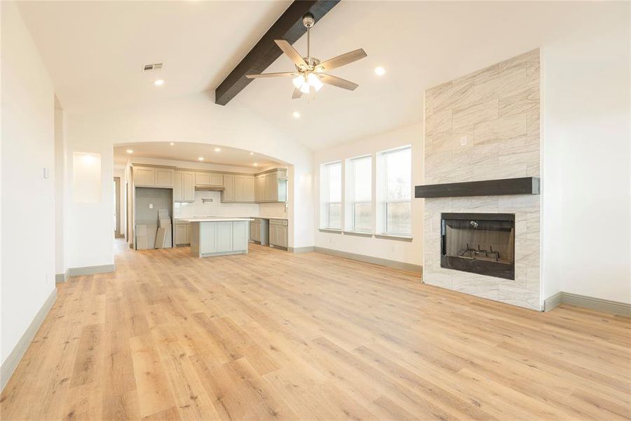 Unfurnished living room with light wood finished floors, ceiling fan, and a tile fireplace