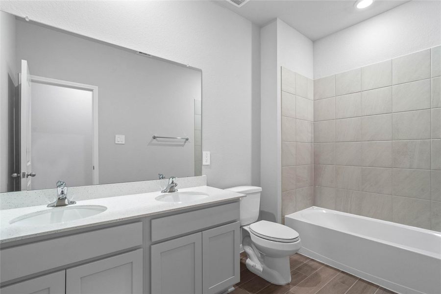 A streamlined secondary bathroom providing a functional tub/shower combination, dual sink vanity with modern fixtures seamlessly blending practicality and style.
