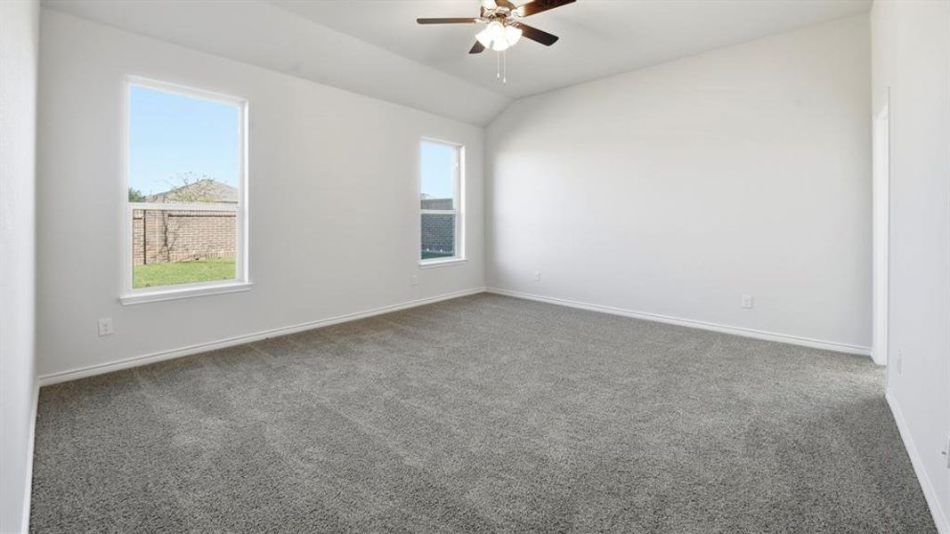 Spacious room featuring gray carpet, vaulted ceiling, and two large windows providing abundant natural light