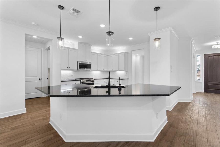 Kitchen featuring stainless steel appliances, a sink, baseboards, dark countertops, and ornamental molding Kitchen featuring stainless steel appliances, a sink, baseboards, dark countertops, and ornamental molding