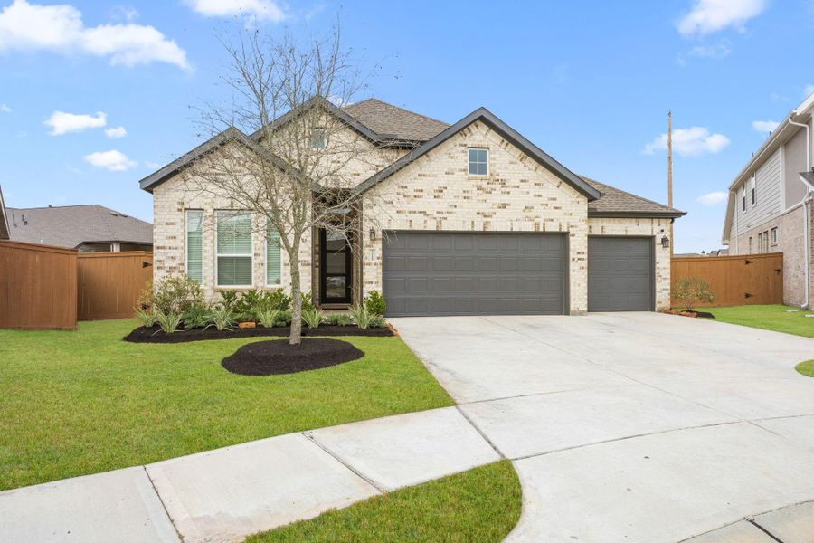 Fresh landscaping frames the driveway and entry, offering a polished first impression in a neighborhood known for newer construction and convenient access to major thoroughfares. Grass has been digitally enhanced for marketing purposes.