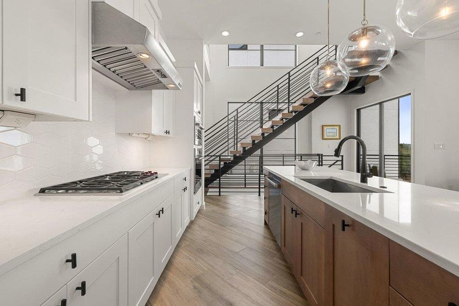 Modern kitchen featuring a gas cooktop, stainless steel range hood, white shaker cabinetry, and a hexagon tile backsplash