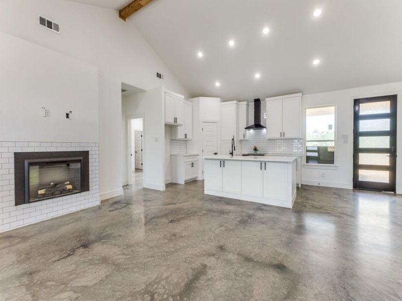 Kitchen with wall chimney range hood, marble floors, beamed ceiling, decorative backsplash, and white cabinets