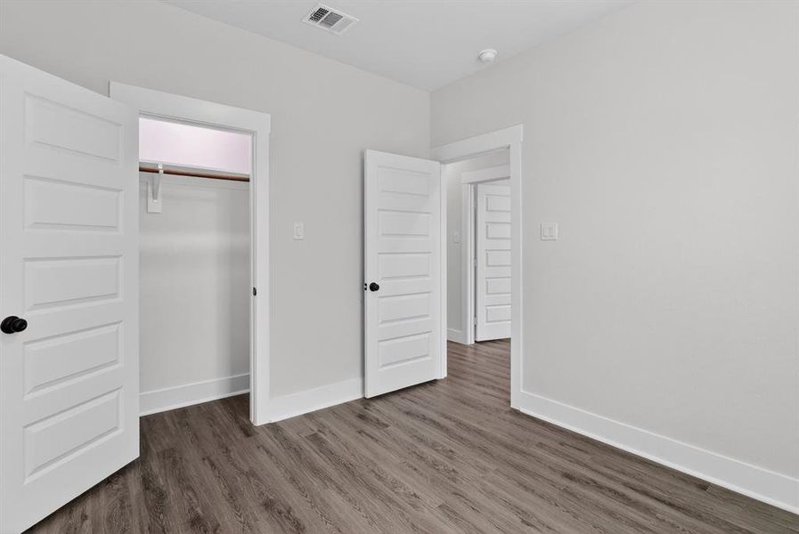 Interior room featuring wood-finish flooring, white walls, and a window with blinds