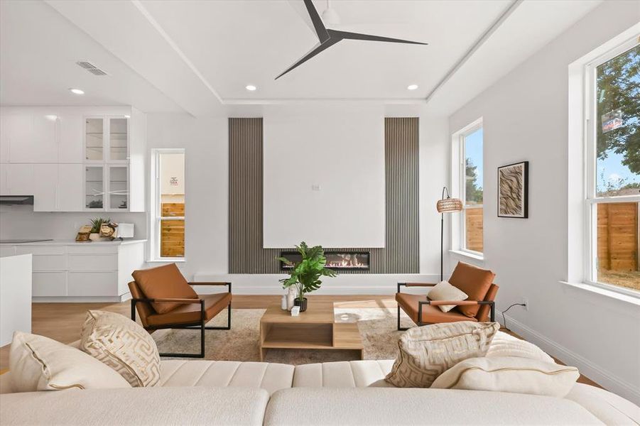 Living room featuring a glass covered fireplace, light wood-type flooring, ceiling fan, and recessed lighting Living room featuring a glass covered fireplace, light wood-type flooring, ceiling fan, and recessed lighting