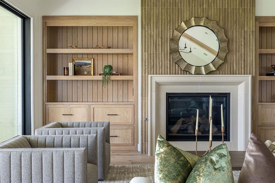 Living area with built in features, light wood-style flooring, and a glass covered fireplace Living area with built in features, light wood-style flooring, and a glass covered fireplace