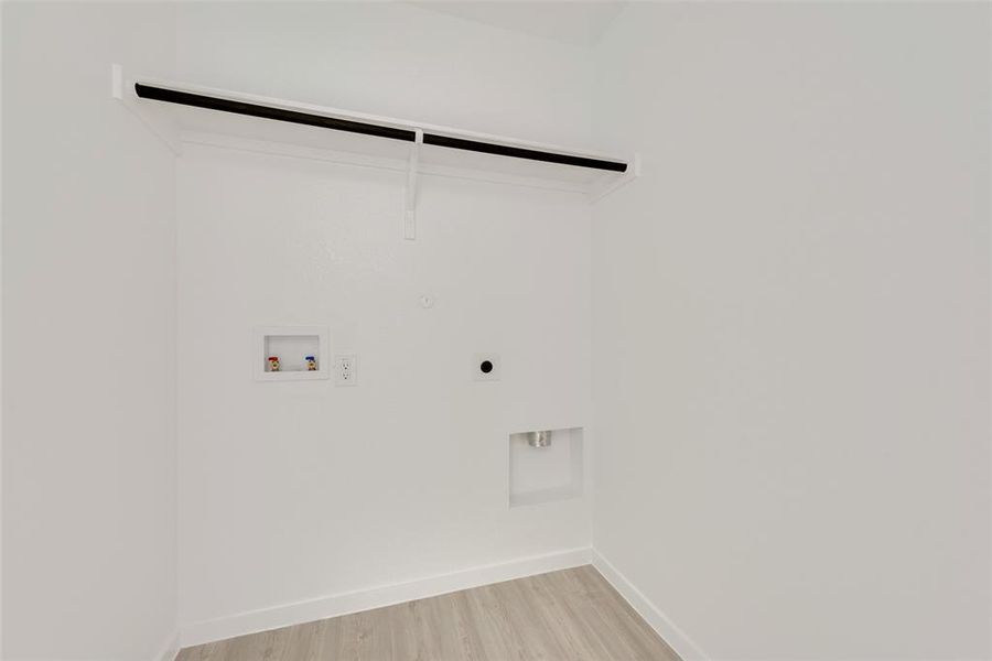 Washroom featuring hookup for an electric dryer, hookup for a washing machine, and light hardwood / wood-style flooring