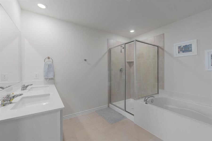 Bathroom featuring a garden tub, a stall shower, tile patterned flooring, and a sink