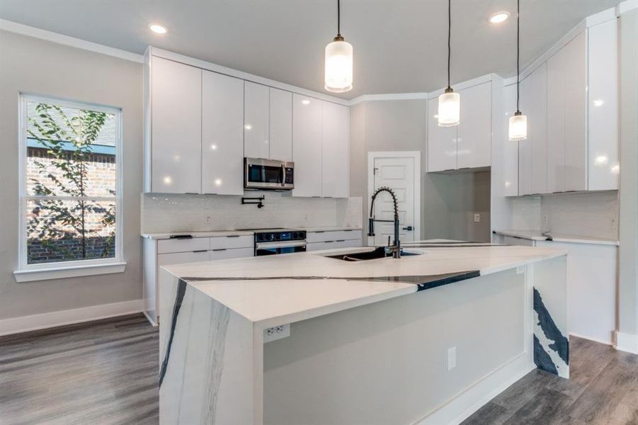 Kitchen featuring light stone countertops, modern cabinets, hanging light fixtures, tasteful backsplash, and dark wood-style flooring